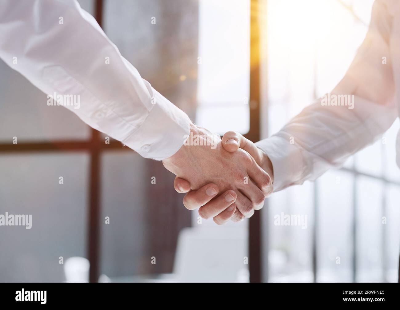 Two businessmen shake hands on the background of empty modern office, signing of a contract concept, close up Stock Photo