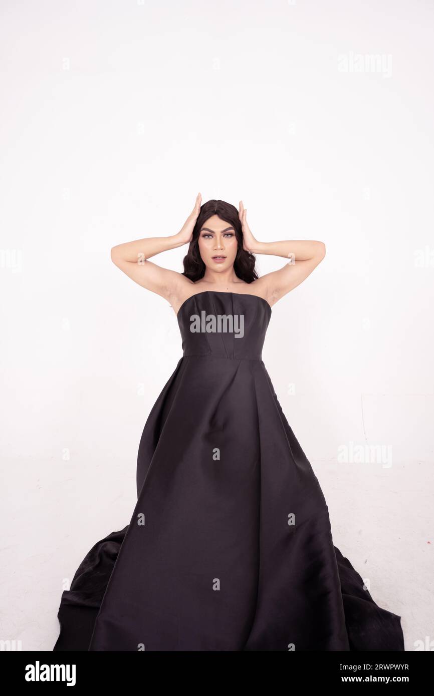 A whole body of an Asian woman in a black dress poses in a white studio with dark brown hair Stock Photo