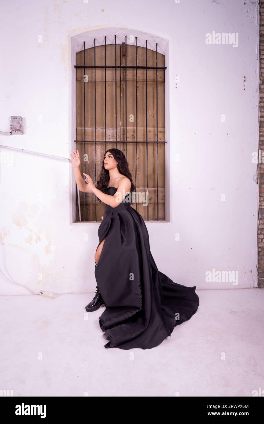 Sad Asian woman standing in front of the brown wooden window while wearing a black dress inside the studio Stock Photo
