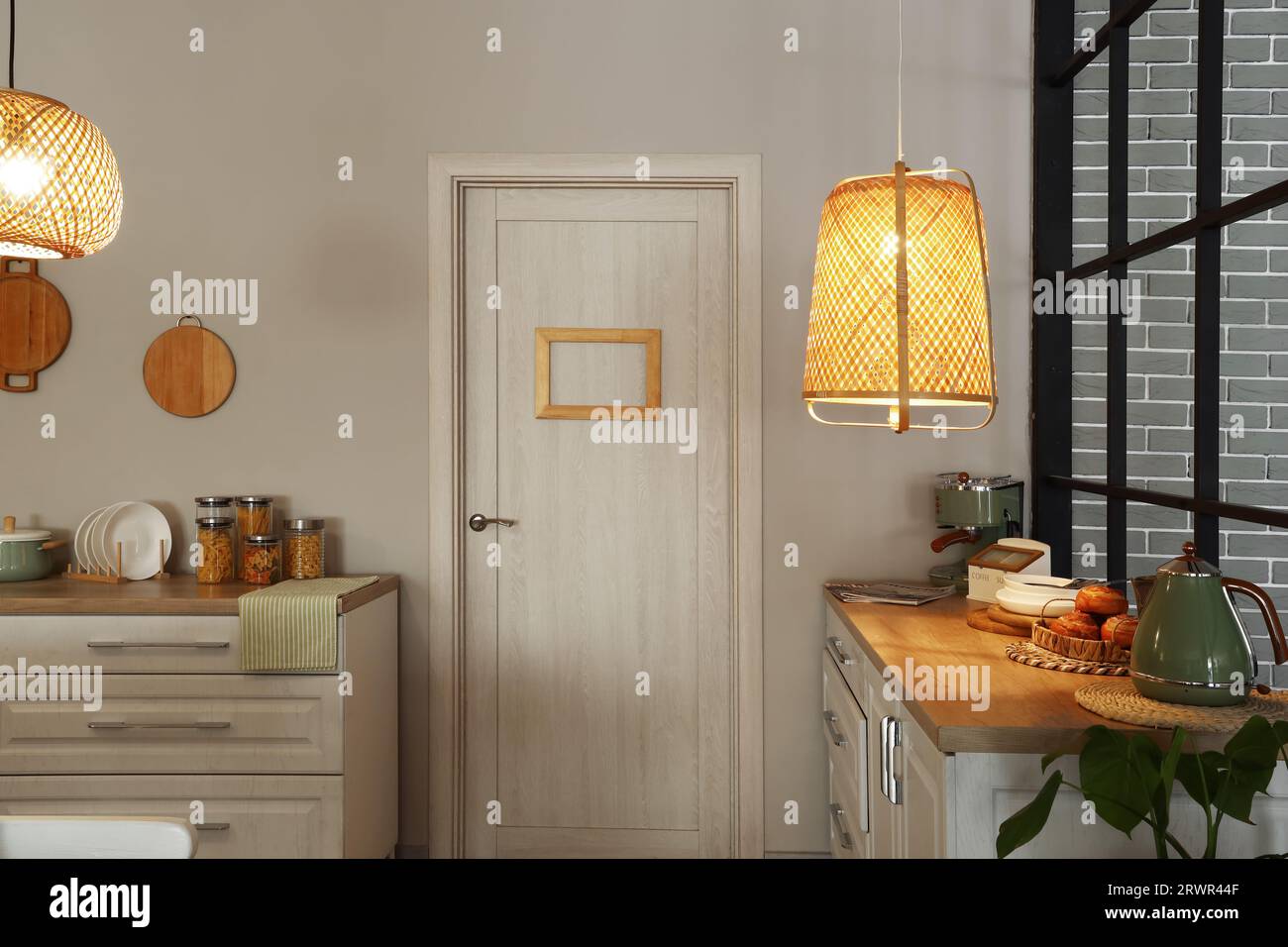 Interior of modern kitchen with glowing lamps, white counters and door ...