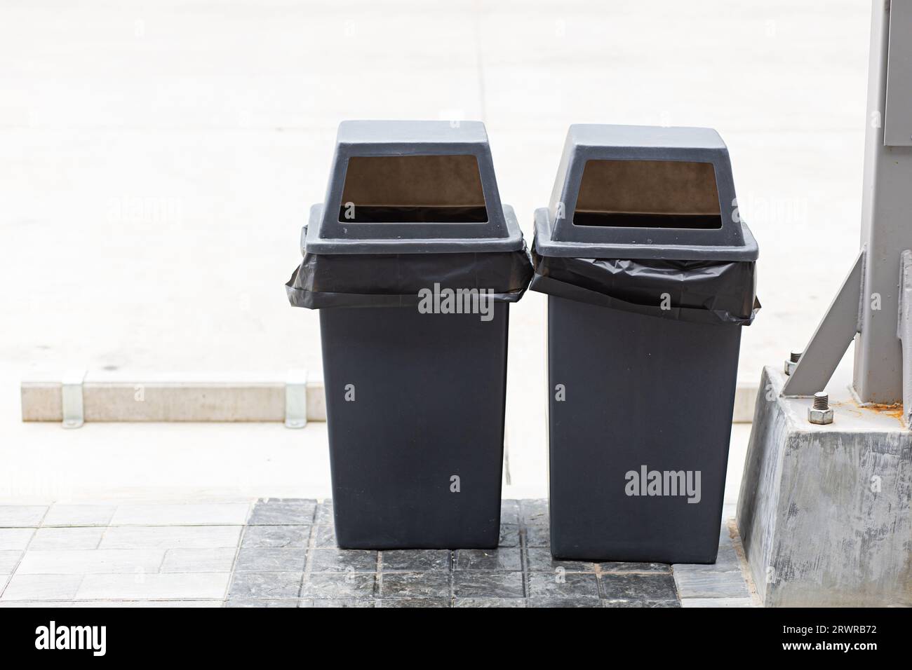 Separation of waste Two black trash cans are placed in a public place on the roadside waiting for garbage collectors to help reduce waste, help global Stock Photo