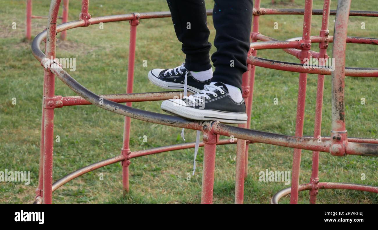 Close-up of child's feet climbing old schoolyard playground equipment Stock Photo