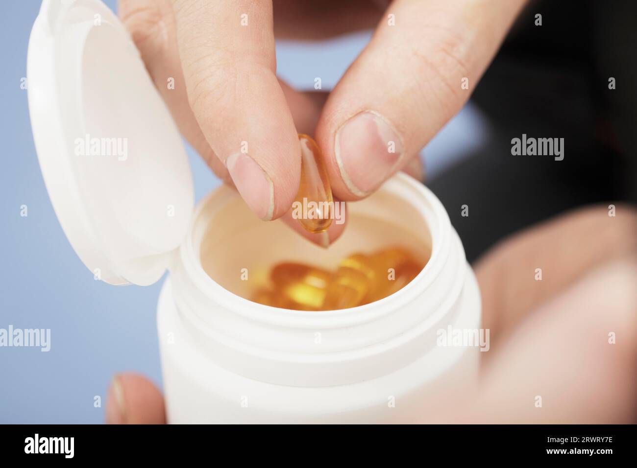 Fingers taking Omega 3 fish oil capsule from a bottle Stock Photo