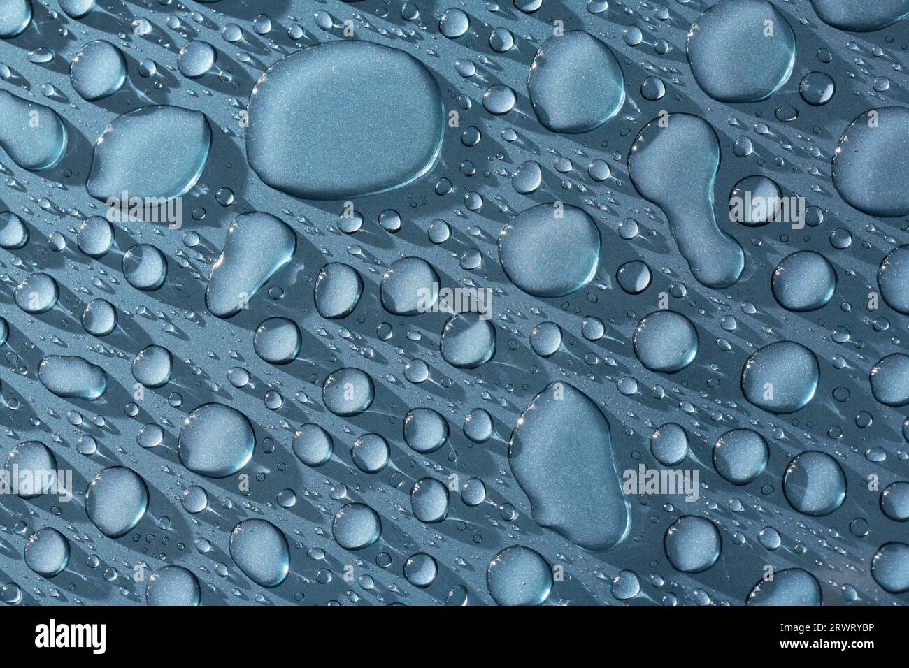 Water beads on a metallic blue car. The image may appear noisy, but it