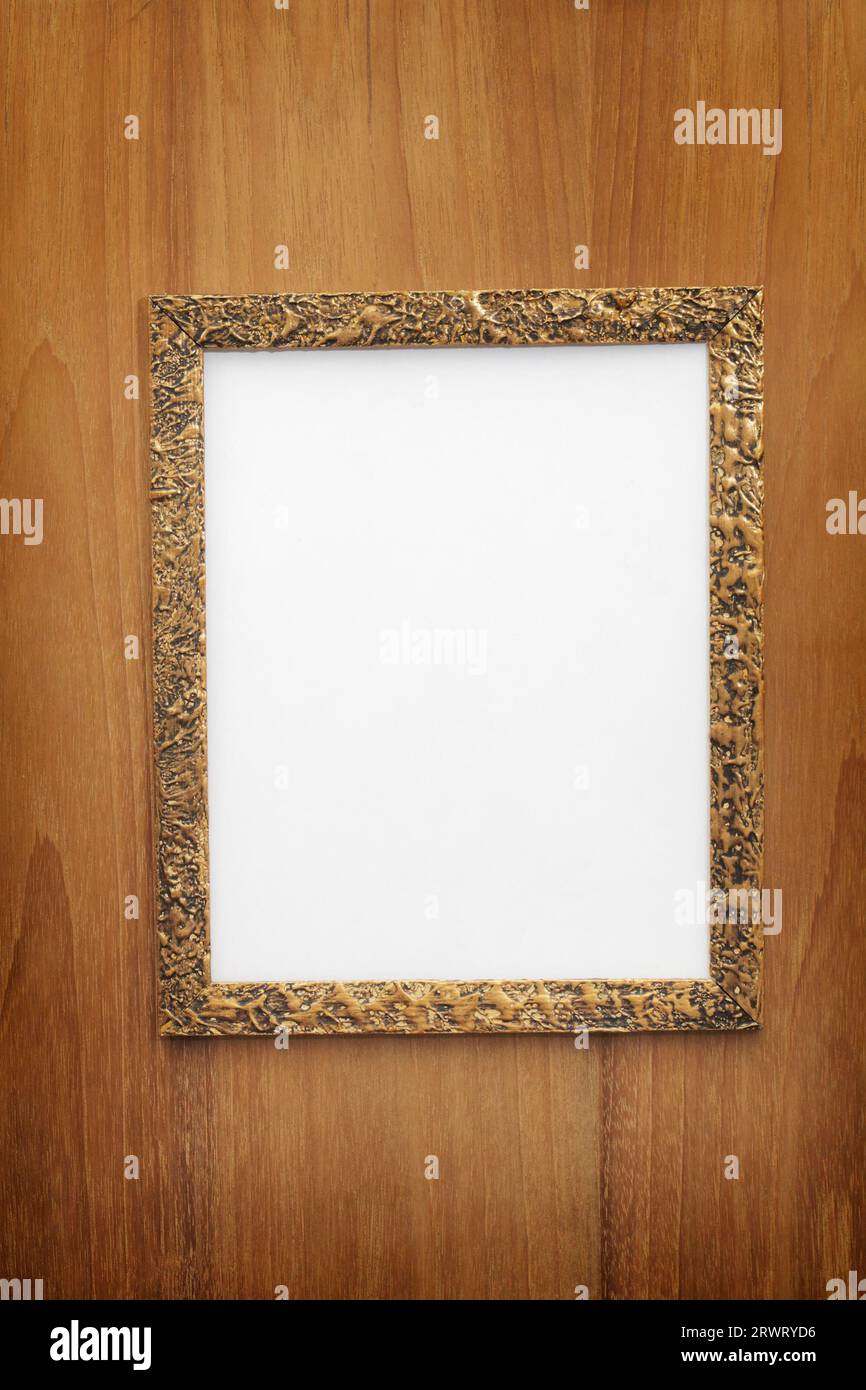 Old gilded photo frame with blank paper on wooden wall Stock Photo