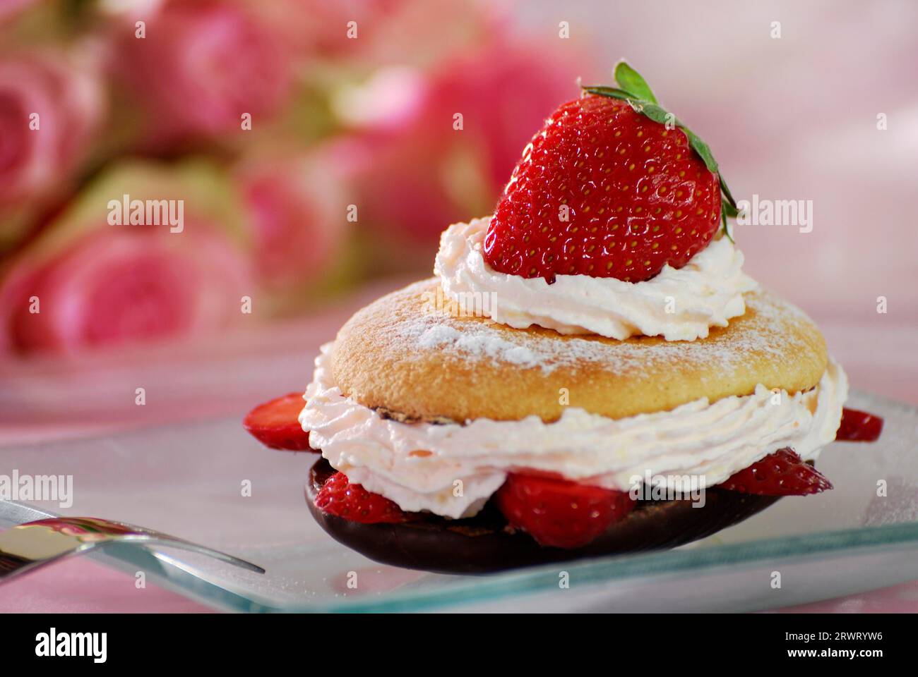 Strawberry tartlet on a pink tablecloth with roses in the background. Strawberry Tartlet on a table with pink roses in the background Stock Photo