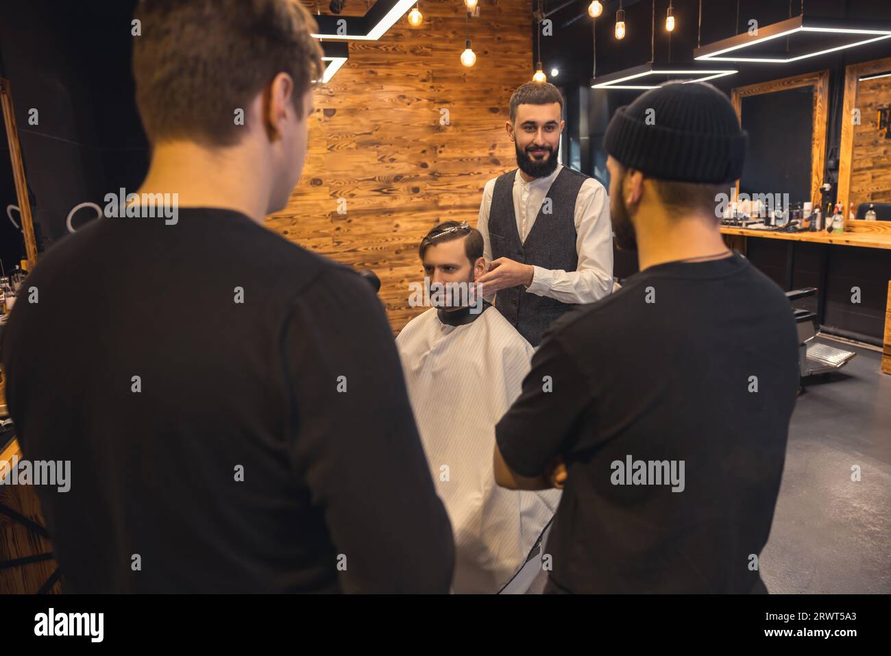 Barber teaches student to make men's hairstyles on model Stock Photo