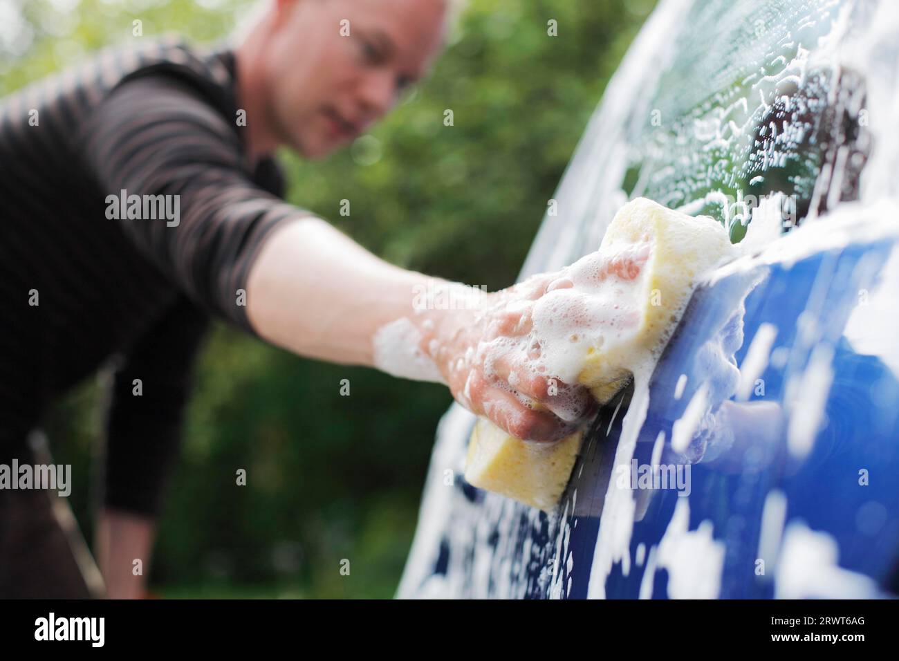 A Man washing a car with a sponge. Short depth of field, the sharpness