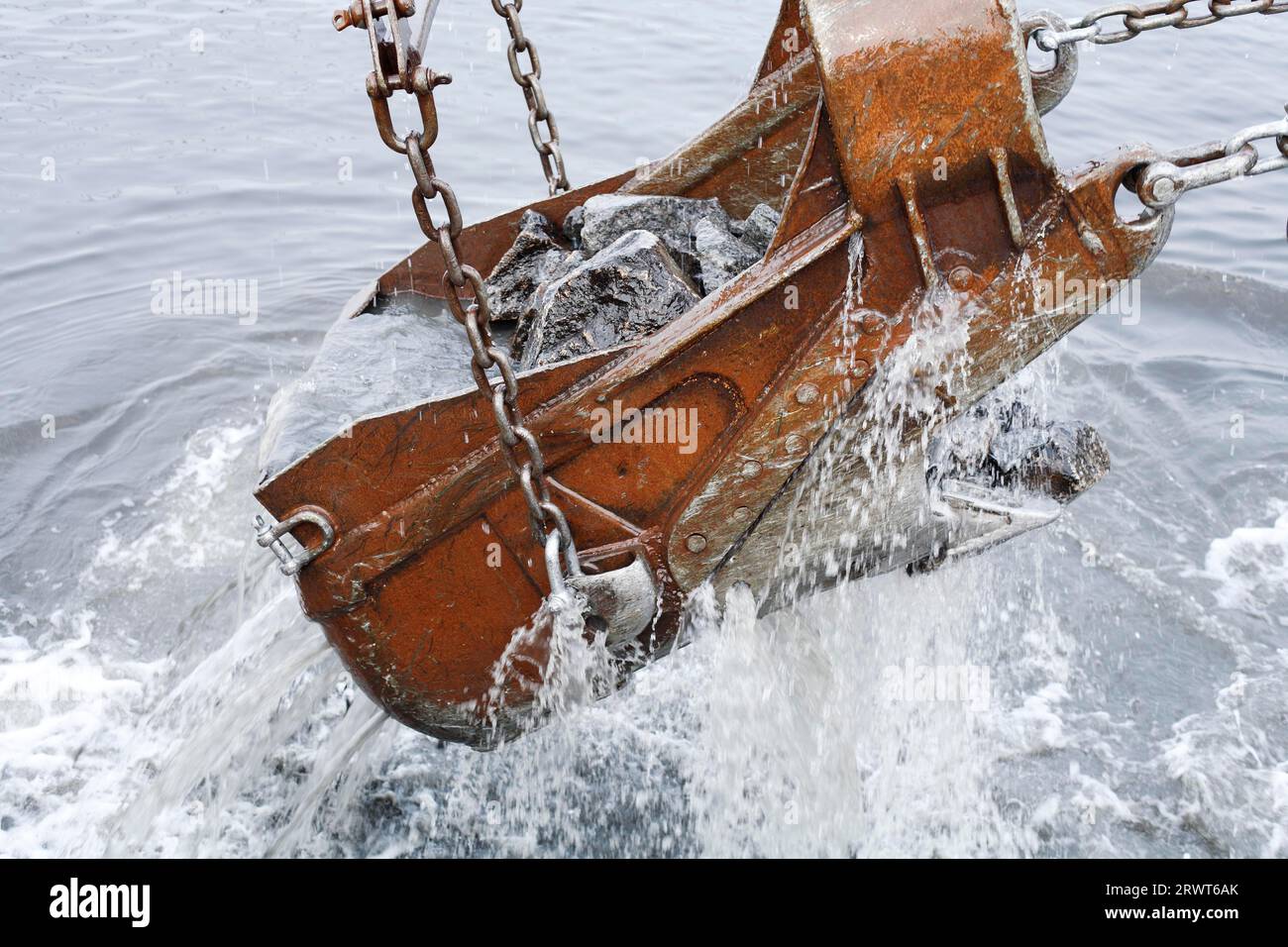 A Dragline excavator bucket dredging in water Stock Photo