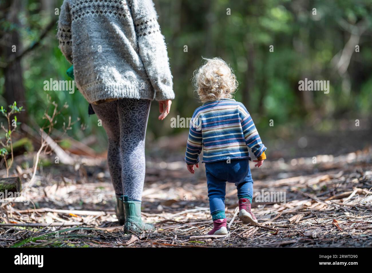 Mother with baby in a carrier on her chest on a hike, taking a bush