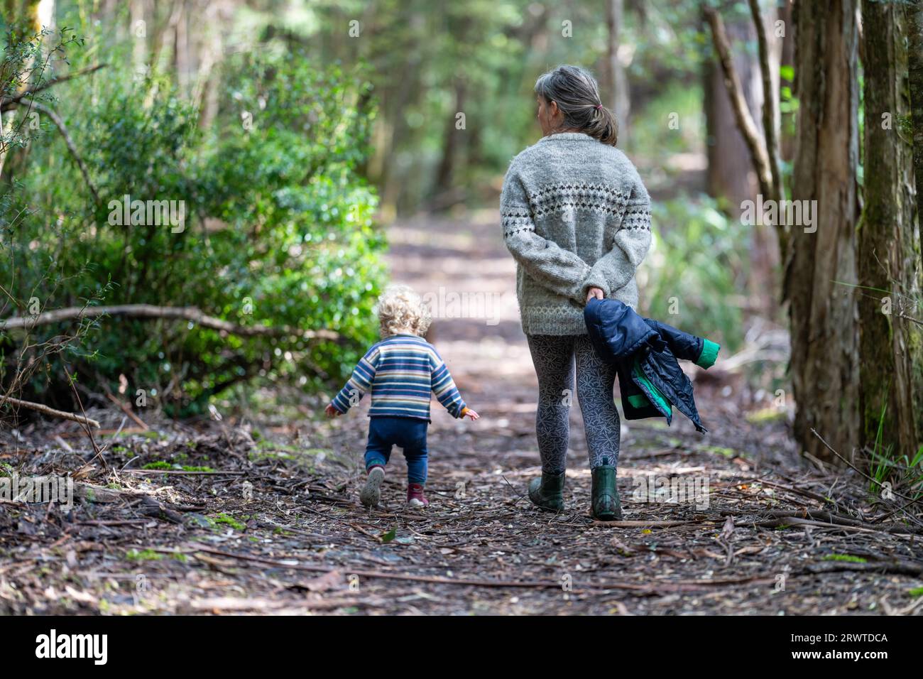 Mother with baby in a carrier on her chest on a hike, taking a bush