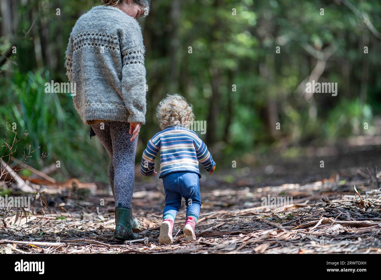 Mother with baby in a carrier on her chest on a hike, taking a bush