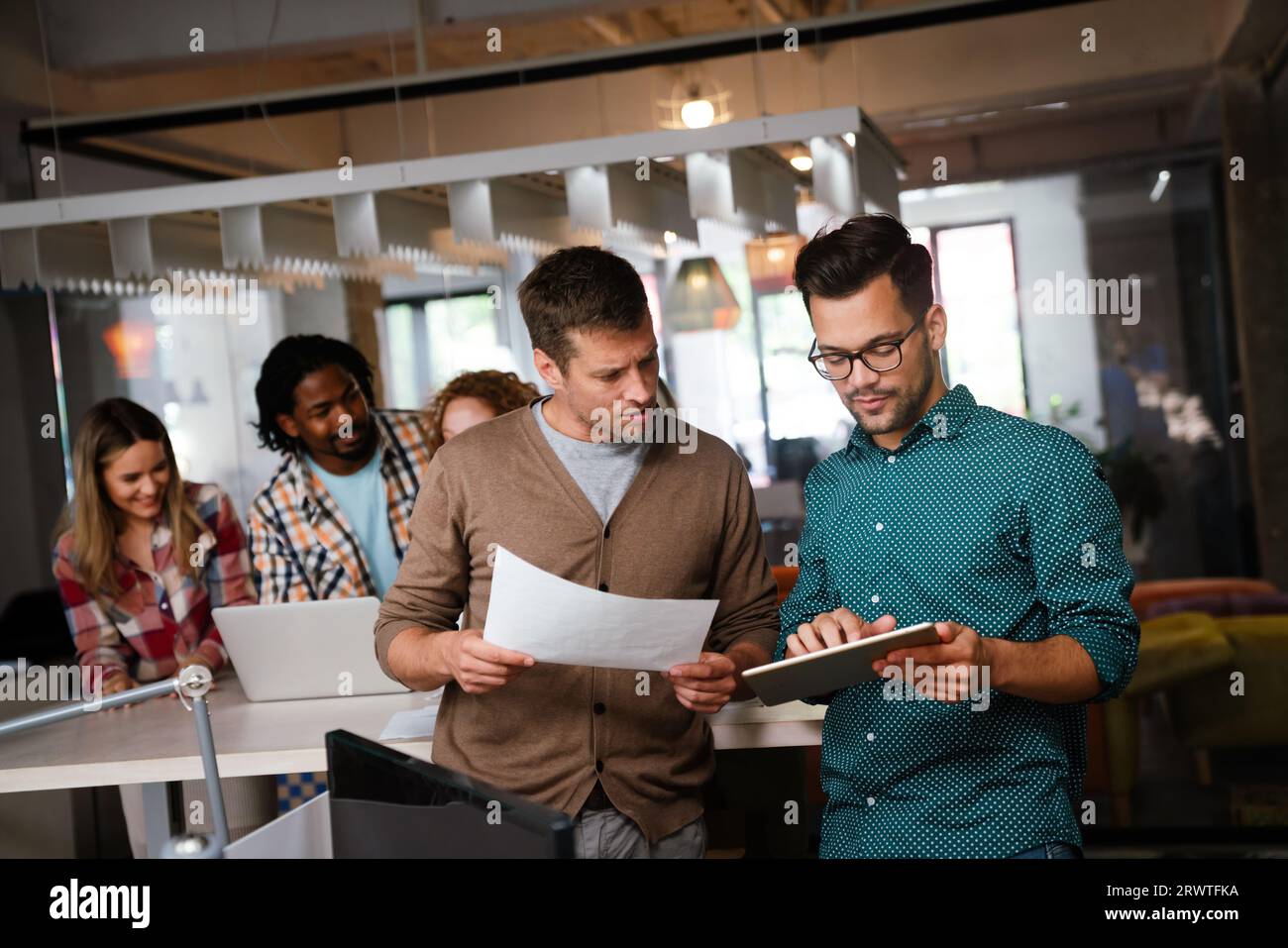 Diverse business colleagues gather in boardroom brainstorm discuss financial statistics together Stock Photo