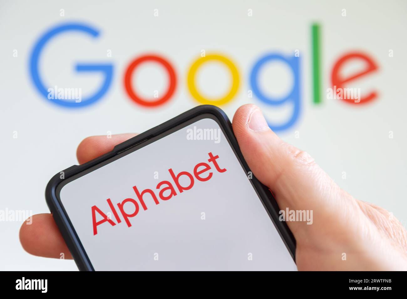 Stuttgart, Germany - July 20, 2023: Hand holding a mobile phone with Google and Alphabet logo of the computer hardware software manufacturer screen in Stock Photo