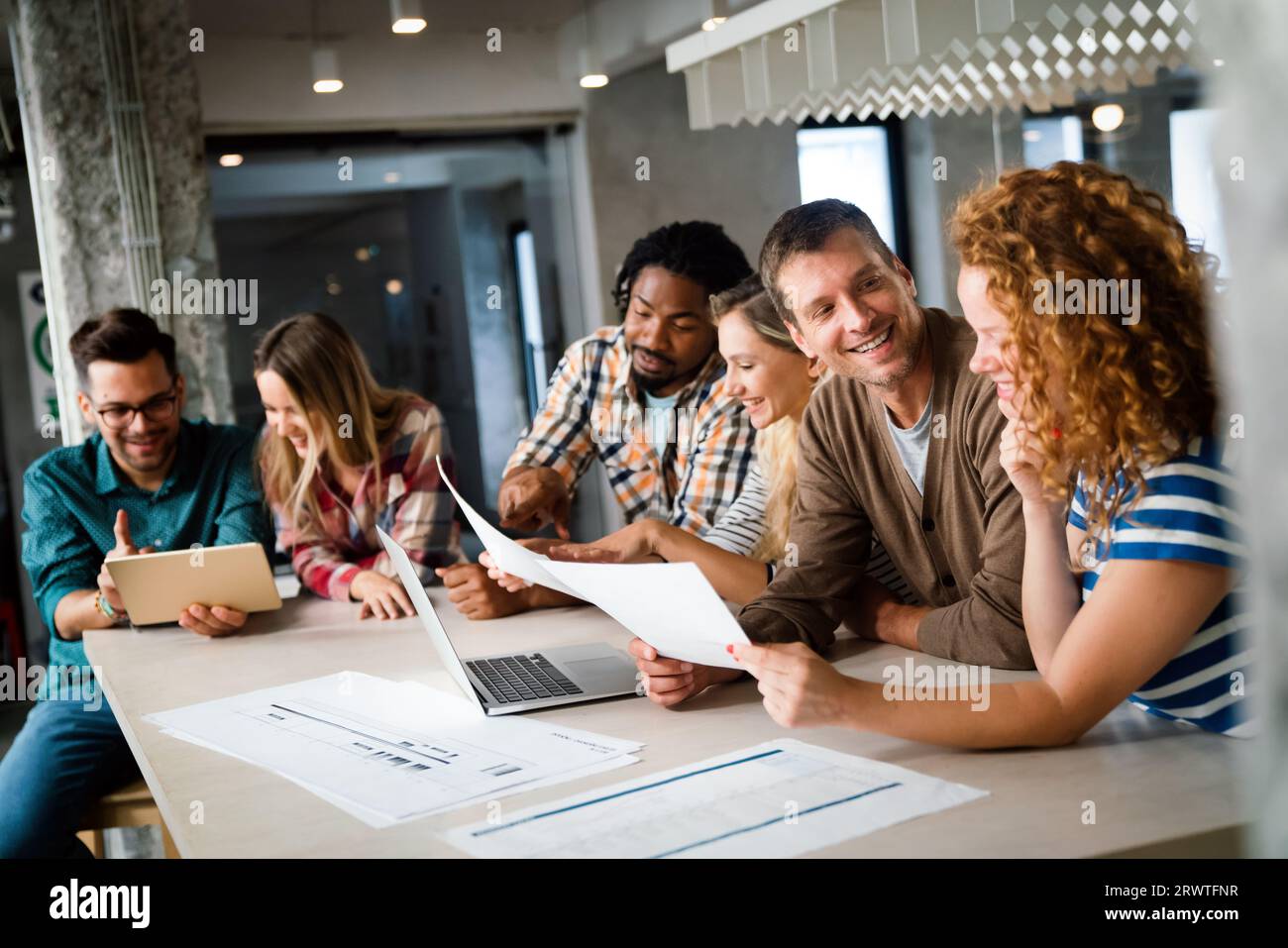 Smiling diverse colleagues gather in boardroom brainstorm discuss financial statistics together Stock Photo