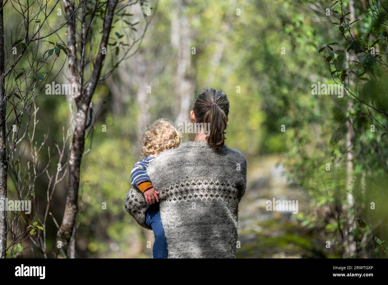 Mother with baby in a carrier on her chest on a hike, taking a bush