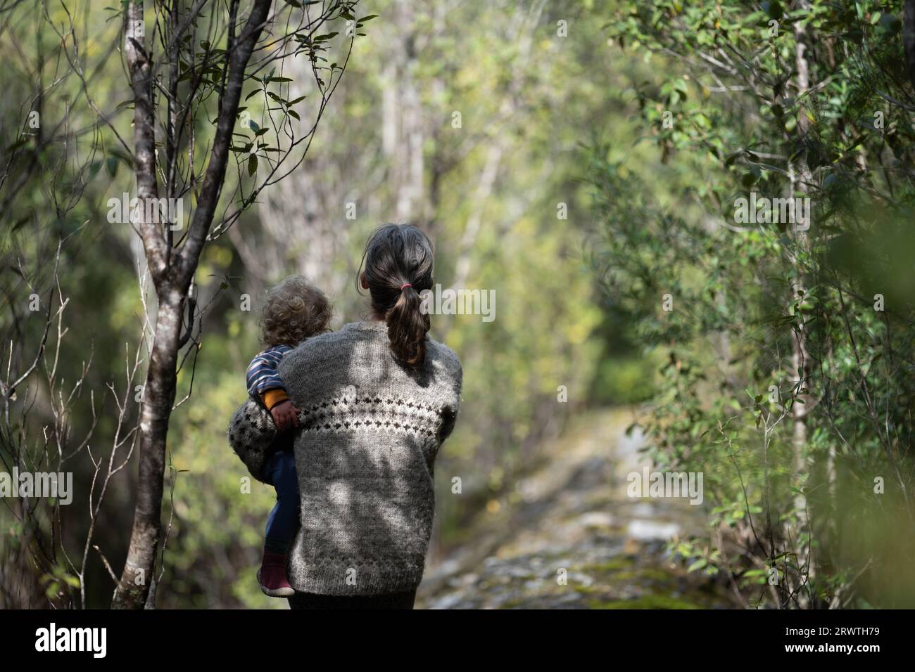 Mother with baby in a carrier on her chest on a hike, taking a bush