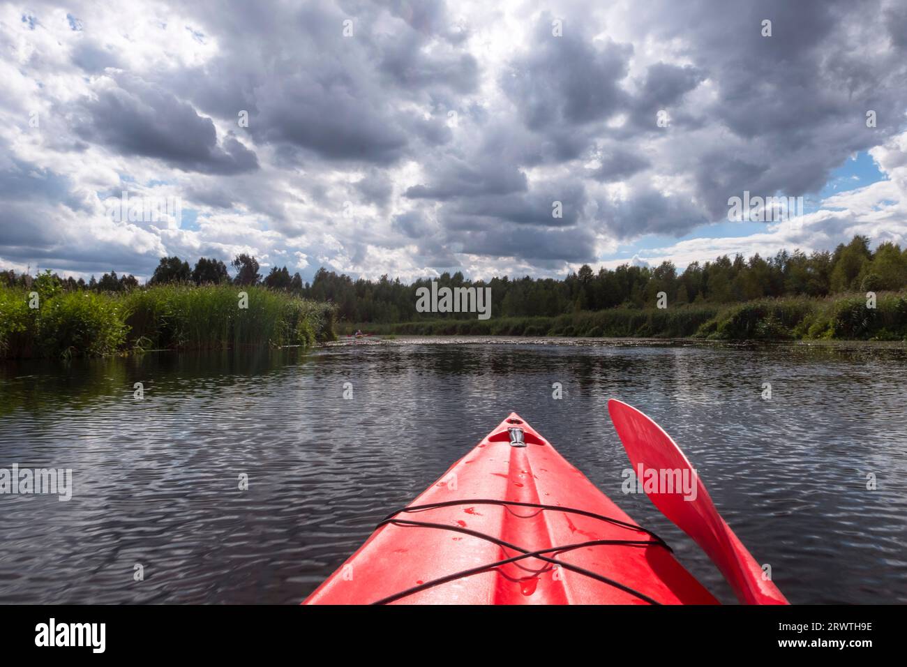 Kayaker point of view. Kayak bow with a view on the river landscape and rushes.   River kayaking during summertime concept . Active vacations in wild Stock Photo