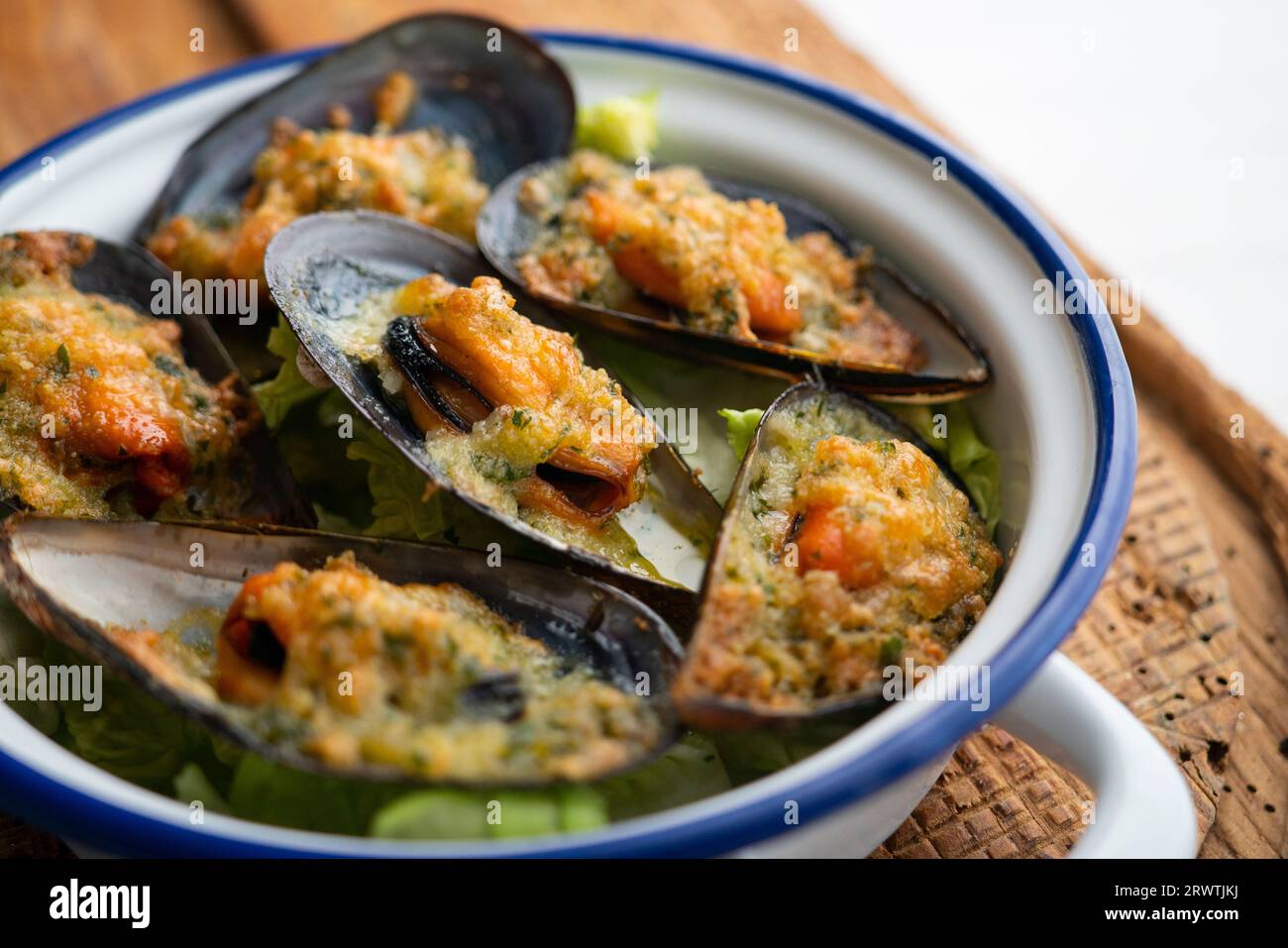 Mussels gratin. Gratin seafood dish with bread and parsley. Stock Photo
