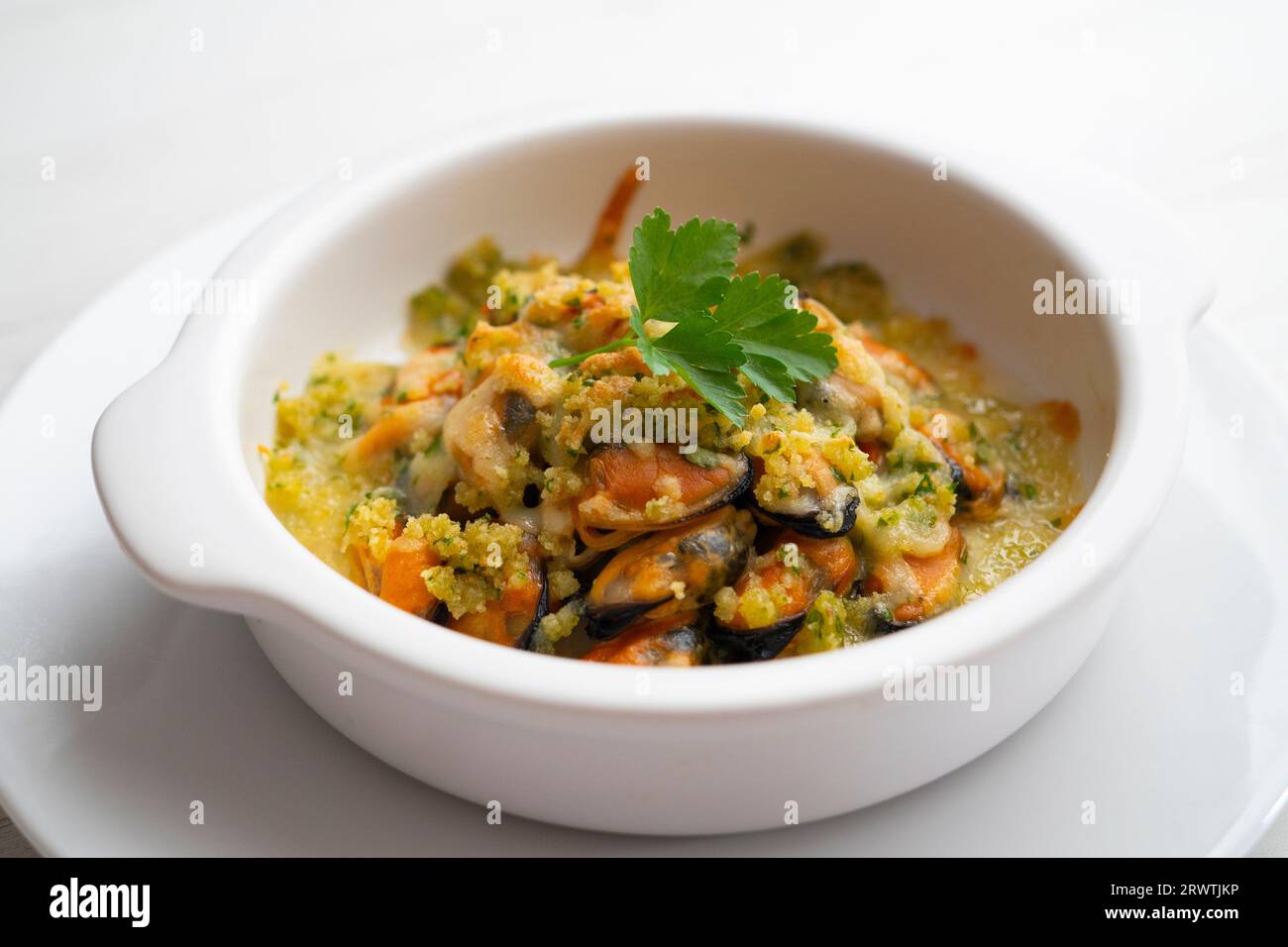 Mussels gratin. Gratin seafood dish with bread and parsley. Stock Photo