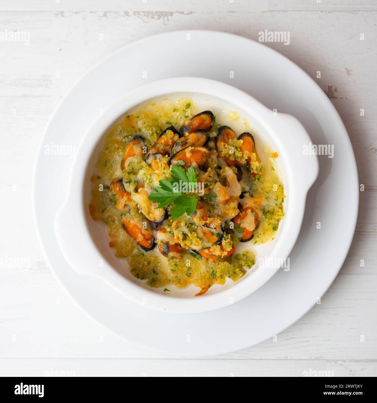 Mussels gratin. Gratin seafood dish with bread and parsley. Stock Photo