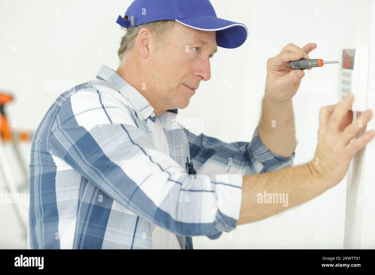 mature electrician installing security alarm on wall Stock Photo Alamy