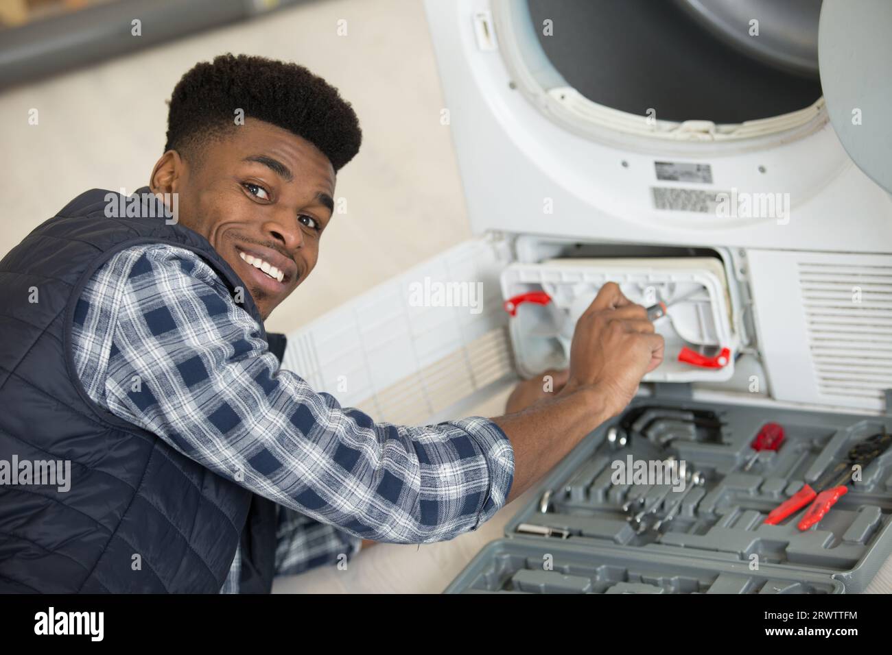 plumber installing washing machine in domestic bathroom Stock Photo