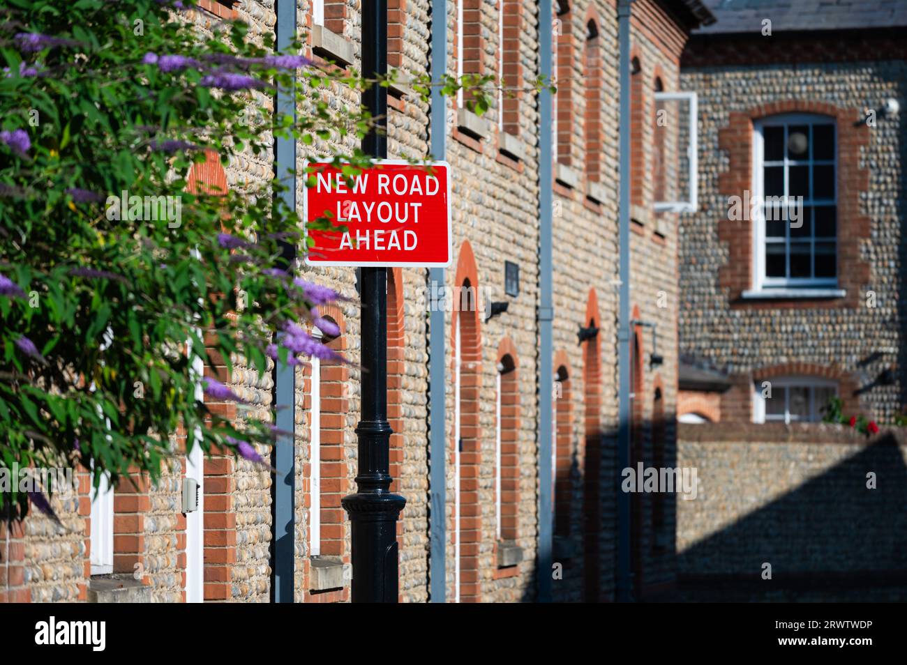 New Road Layout Ahead road sign attached to converted flint and red brick industrial building in the Sussex area of England, UK. Stock Photo