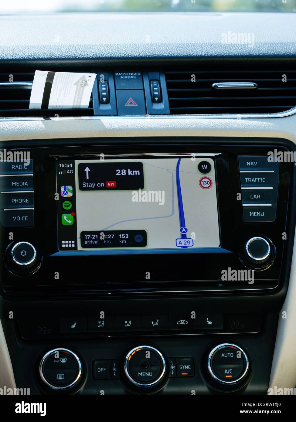 France - Aug 17, 2023: Apple Computers' iOS CarPlay is displayed on the dashboard of a luxury car, featuring navigation maps, a remaining range of 153km, projected arrival time, and turn-by-turn guidance instructions. Stock Photo