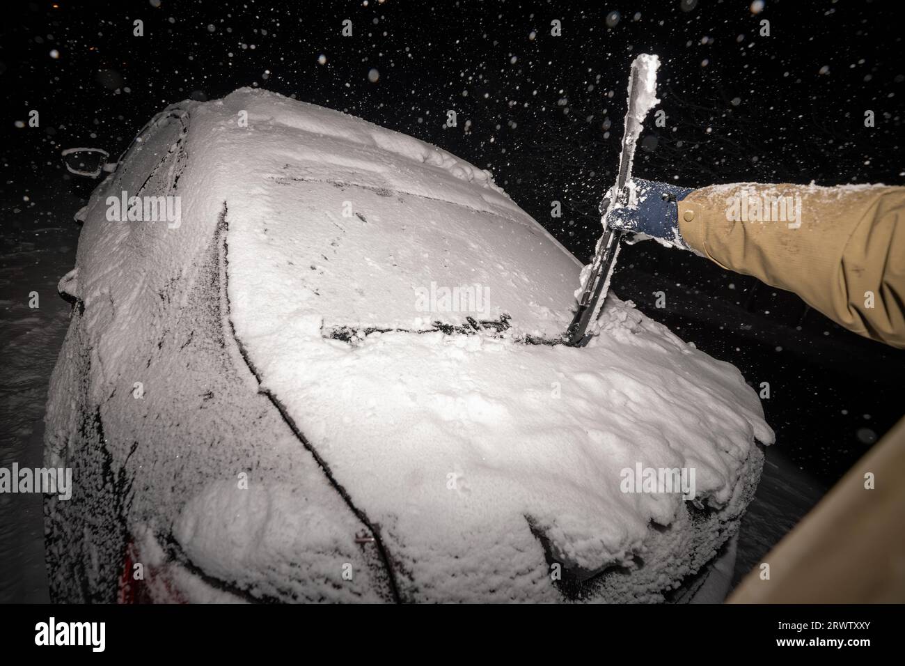 Amidst a snowstorm, a man's hand strives to remove ice and snow from