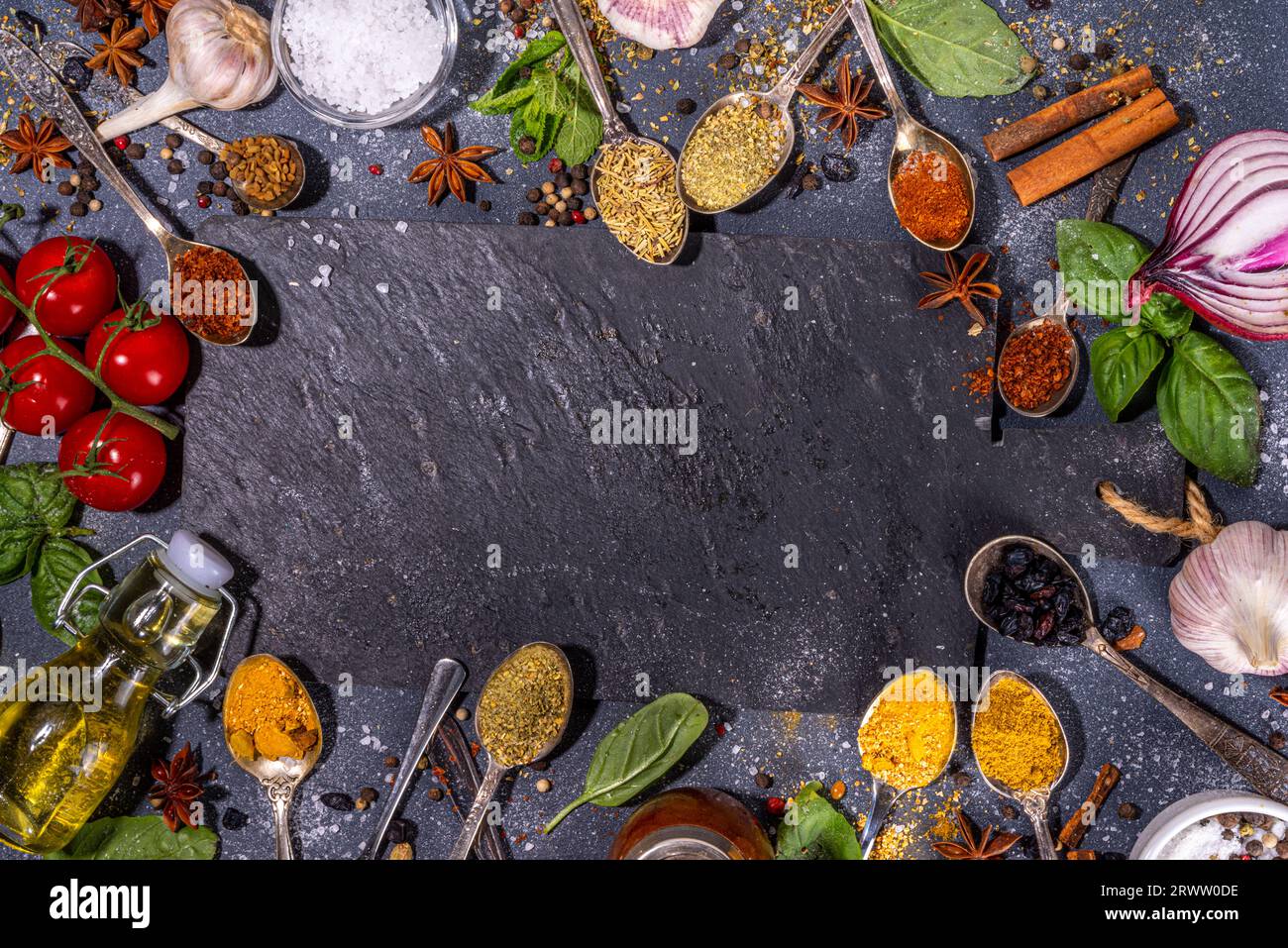 Spices for cooking on dark background . Different seasonings, spices and herbs paprika, pepper, turmeric, salt, basil, mint, cinnamon, garlic, olive o Stock Photo