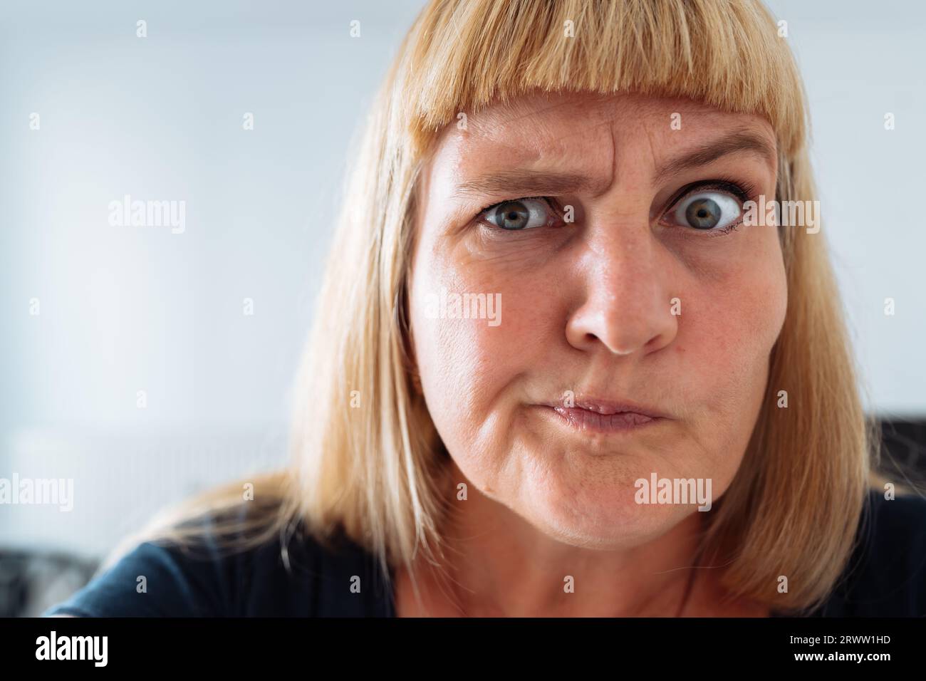 Portrait middle-aged woman, blonde, grimacing in front mirror Stock Photo