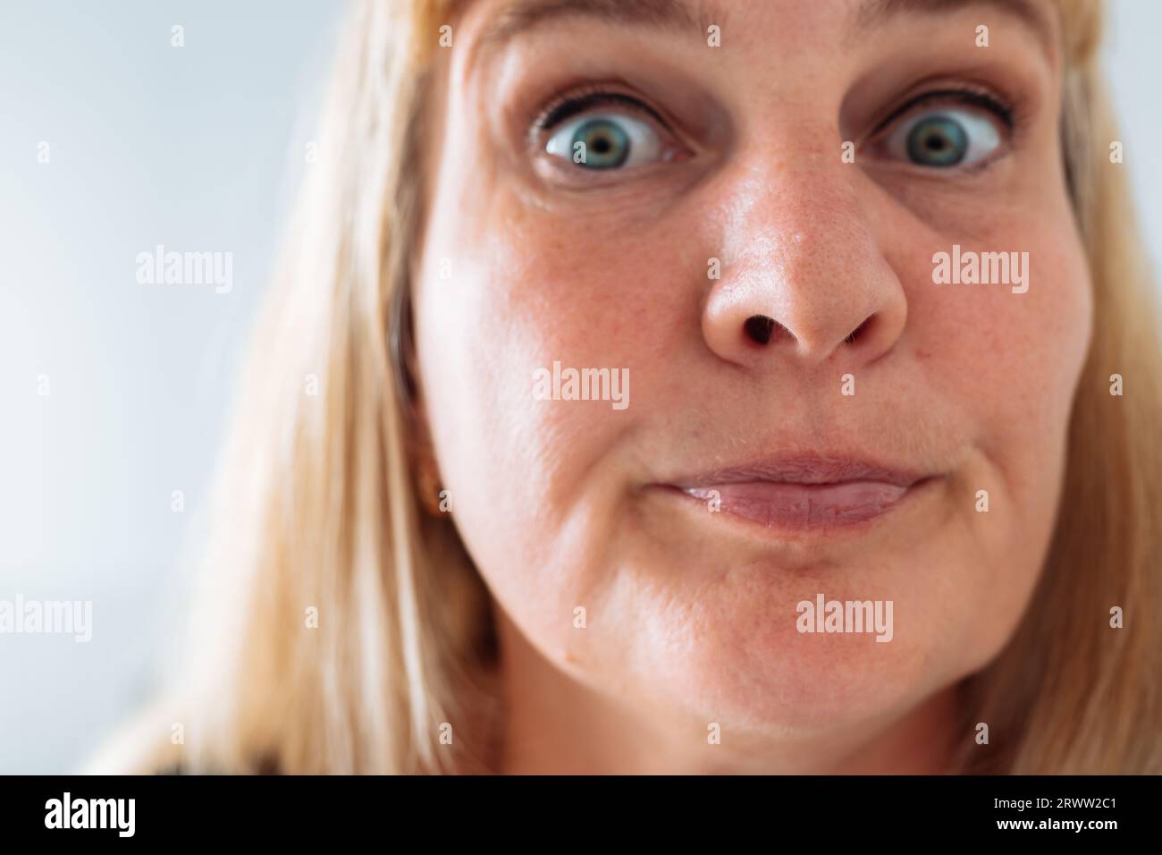 Portrait middle-aged woman, blonde, grimacing in front mirror Stock Photo