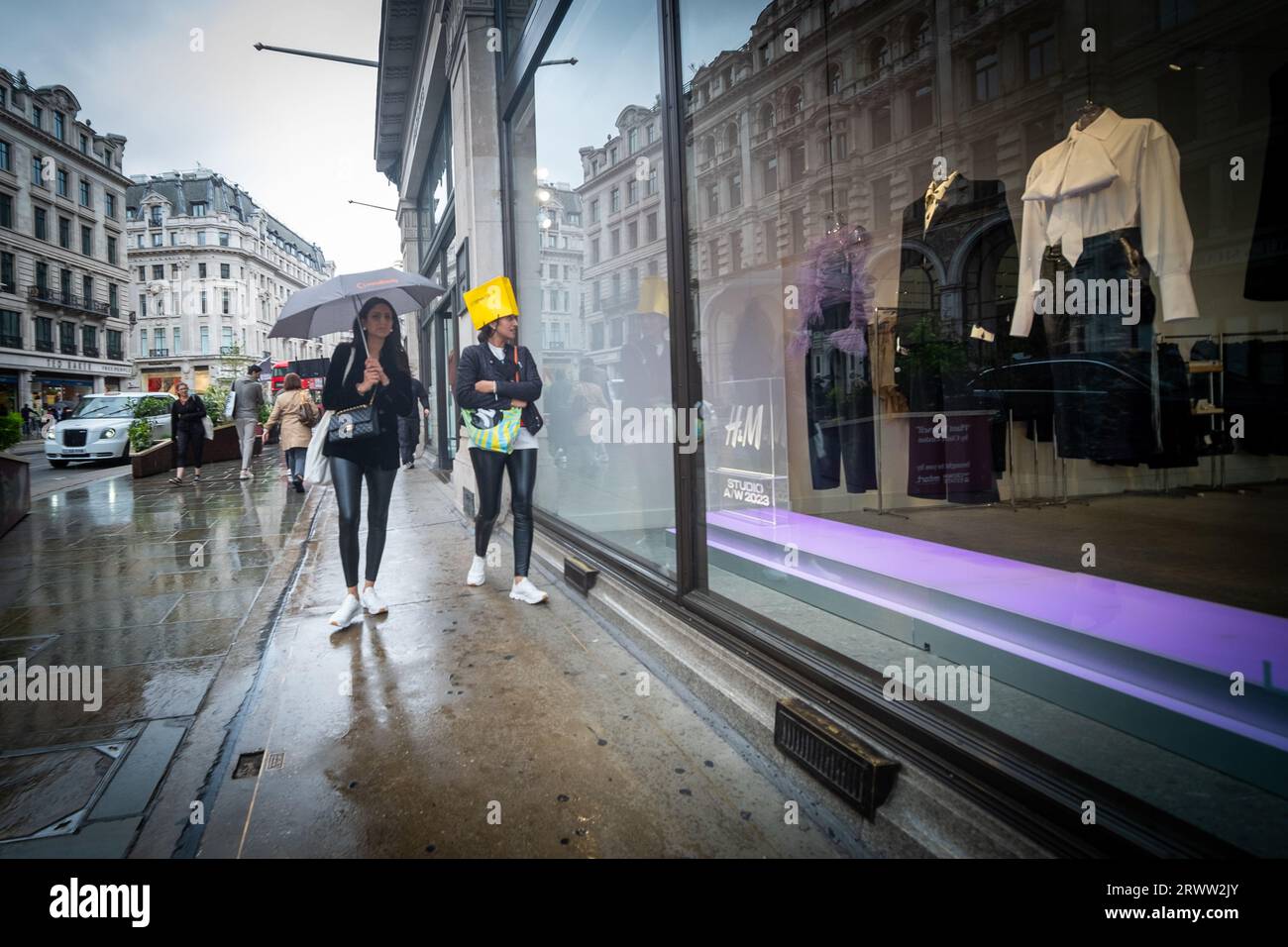 LONDON- SEPTEMBER, 19, 2023: Shoppers on Regent Street caught in the rain- one with a bag on her head Stock Photo