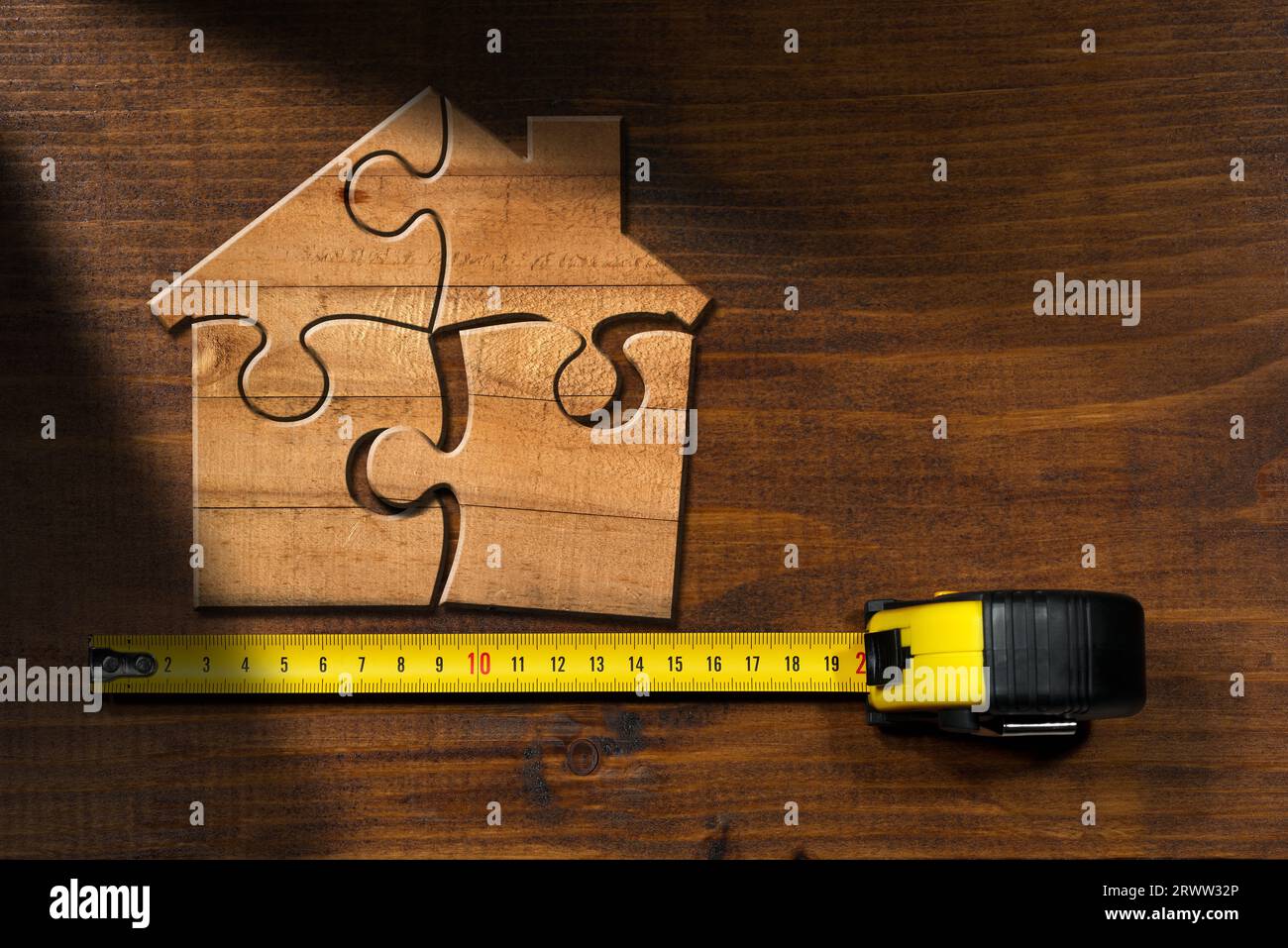 Wooden jigsaw puzzle pieces forming a house shape, on a wooden