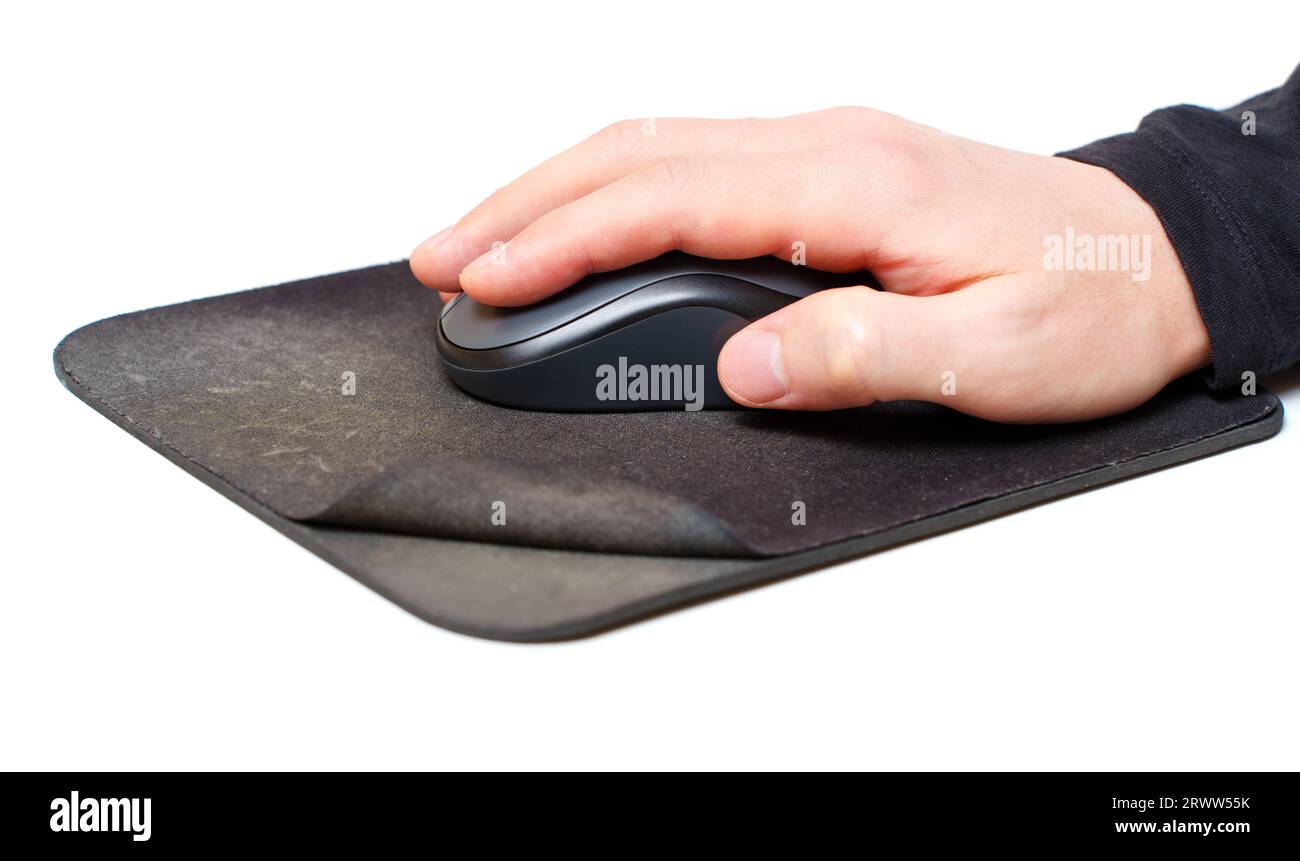 Male hand uses a computer mouse resting on an old, worn mouse pad isolated on white background. Stock Photo