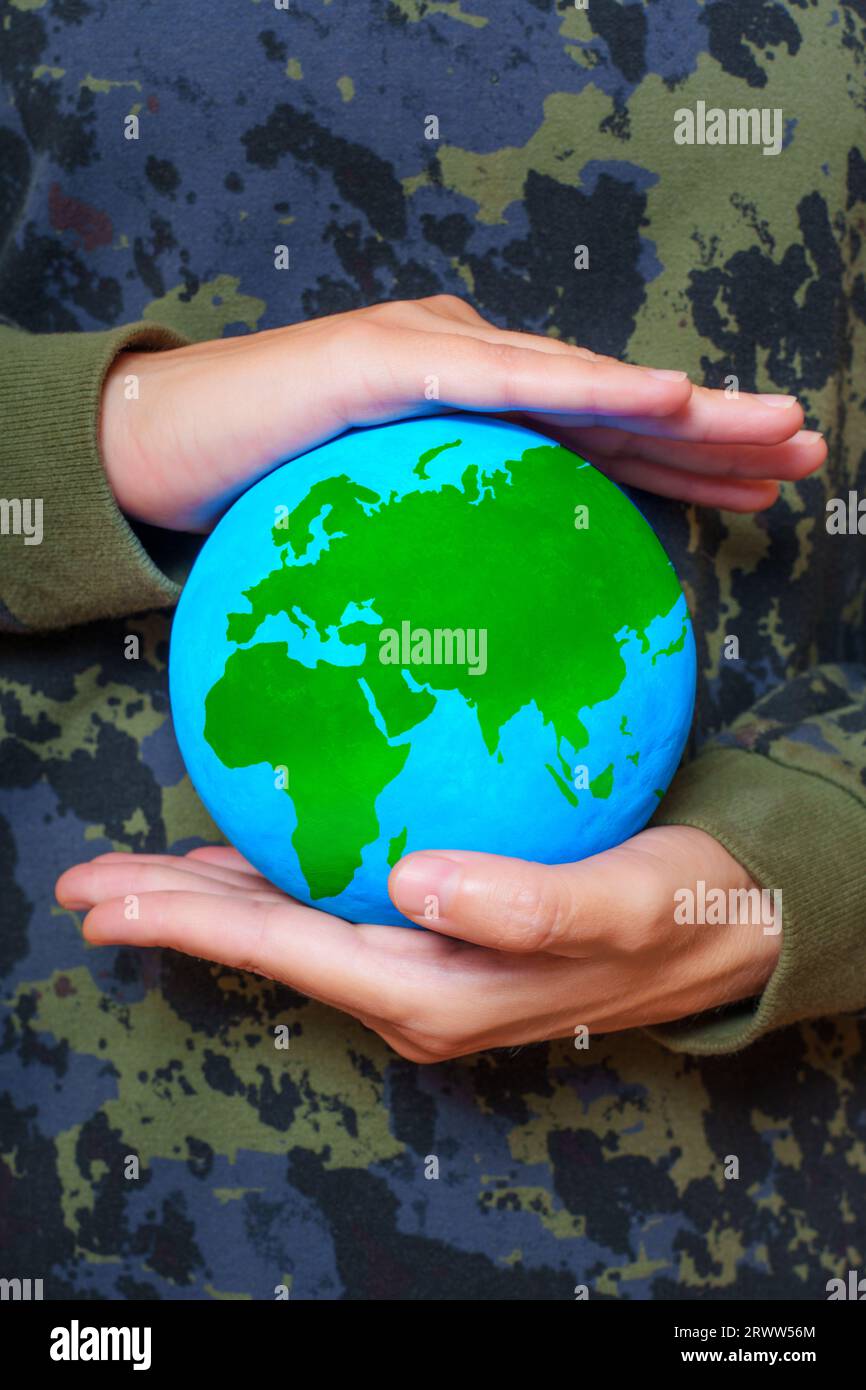 Female wearing camouflage clothing embraces the globe in her hands