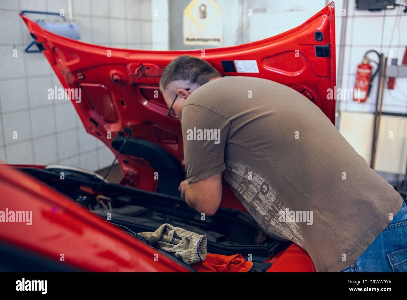 A Man with glasses Maintains a Car in a Garage. Car Repair by an experienced Specialist in a Car Repair Shop. Replacing the oil and filter in the car. Stock Photo