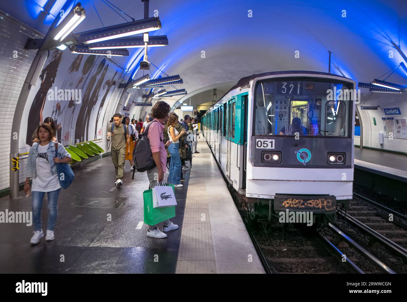 Passengers wait on the platform as a Paris Metro train pulls into Gambetta Station on Line 4 in Paris, France. Stock Photo