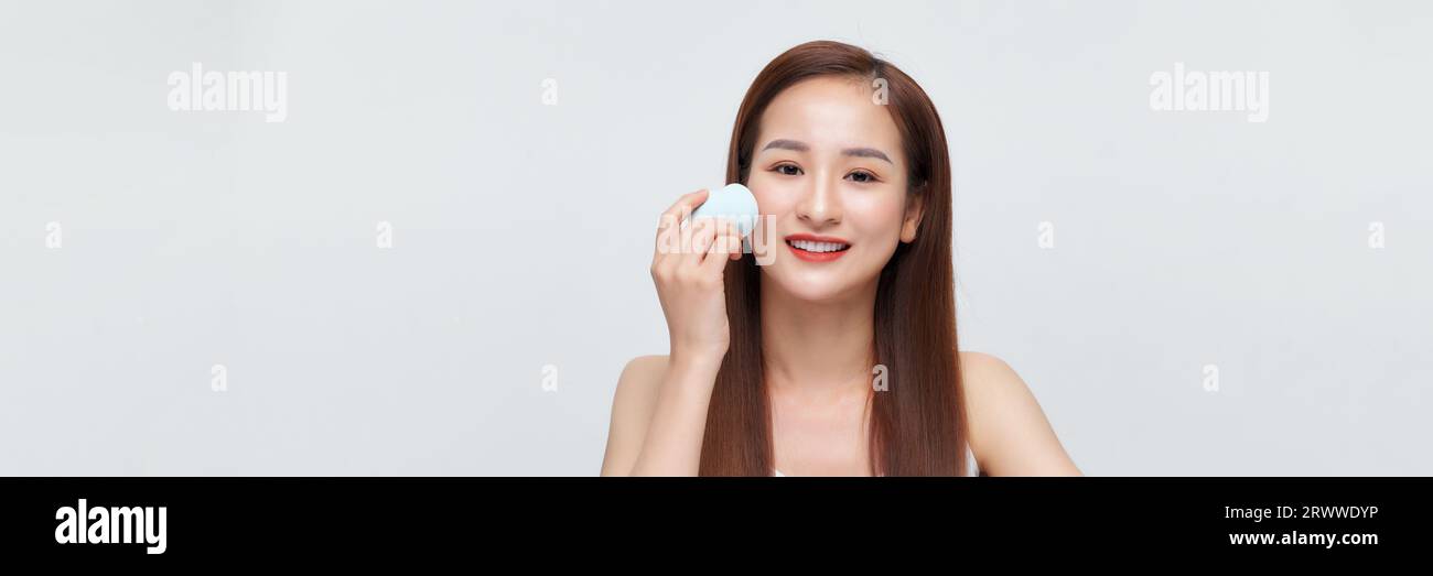 Beautiful young woman applying makeup using beauty blender sponge. Stock Photo
