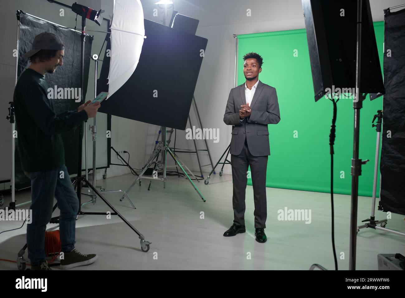 Filming process of TV program with presenter standing against the green