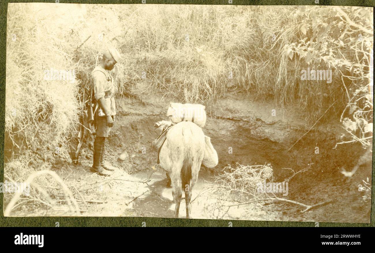 Photograph of a horse reaching the winning post at Nairobi Racecourse, showing European race officials looking downwards from the stewards' enclosure above and two African men behind the fence.  Original manuscript caption: Sept. meeting Nairobi 1919. 'Surprise' winning divided pony h'cap Mr Orr up. Stock Photo