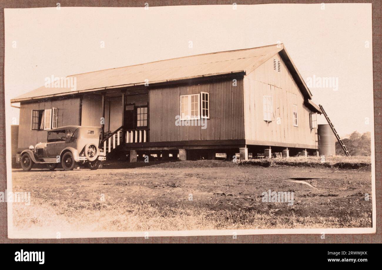 One of a series of images of the Bungeys' second home in Kapsabet in the early 1930s. This image shows the front of the house with a car parked outside. A European couple and their son are in the garden, the boy is playing with a dog. Original page caption: Views of House & garden Kapsabet. Stock Photo