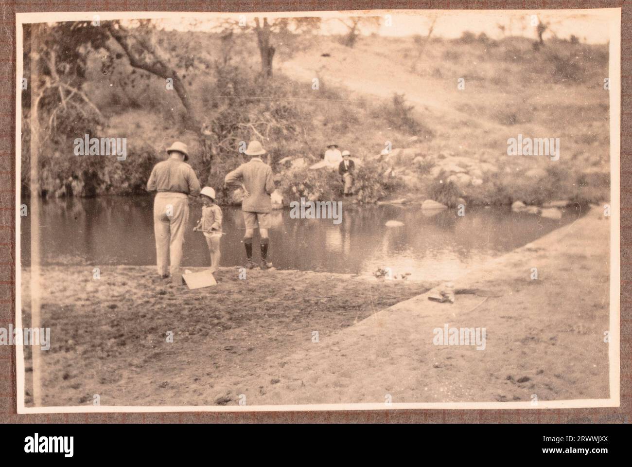 One of a series of images of the Bungeys on a day out with friends, identified in other images as the Manleys. A group of European adults and children wade in the sea next to rocks. A canoe floats in the water beside them. Original manuscript caption: Picnic at 'Likoni', Mombasa Aug: 1927. Stock Photo