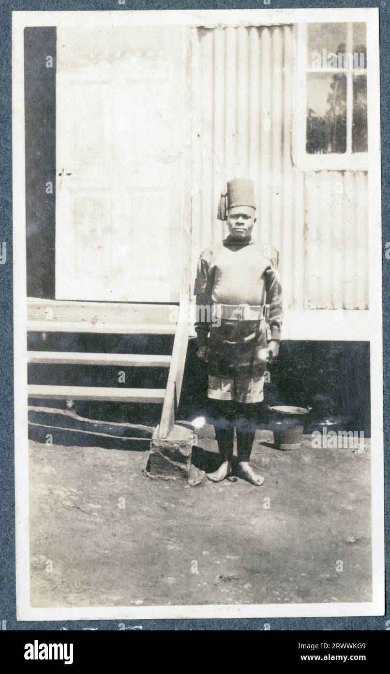 Portrait of an African soldier in K.A.R. uniform standing outside a corrugated iron building. Original manuscript caption: Sgt. Timu 2nd K.A.R. Stock Photo