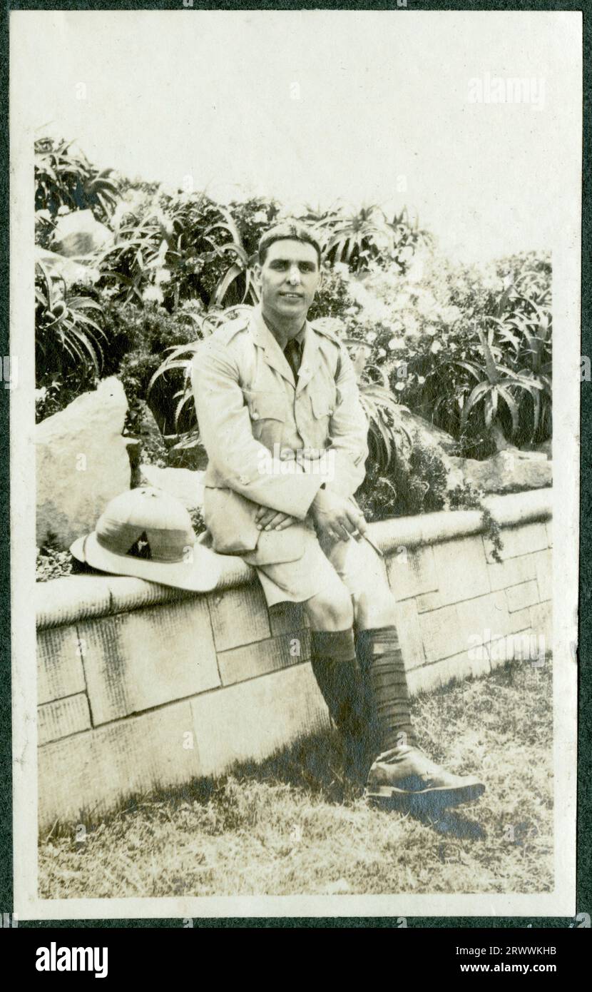 Portrait of a European man in K.A.R. officer's uniform, seated on a wall with his pith helmet next to him. Original manuscript caption: R.Q.M.S. [Regimental Quartermaster Sergeant] Berry 3rd K.A.R. Stock Photo