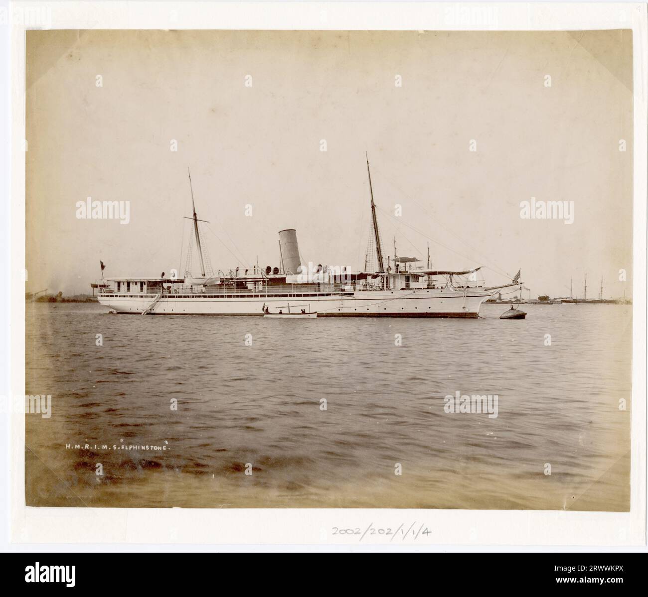 View of a steamship with a single funnel, two masts and two lower decks in a harbour anchorage. Further ships can be seen in the background. Caption inscribed on negative: H.M.R.I.M.S. Elphinstone. Handwritten caption reads: R.I.M.S Elphinstone, Rangoon. Stock Photo