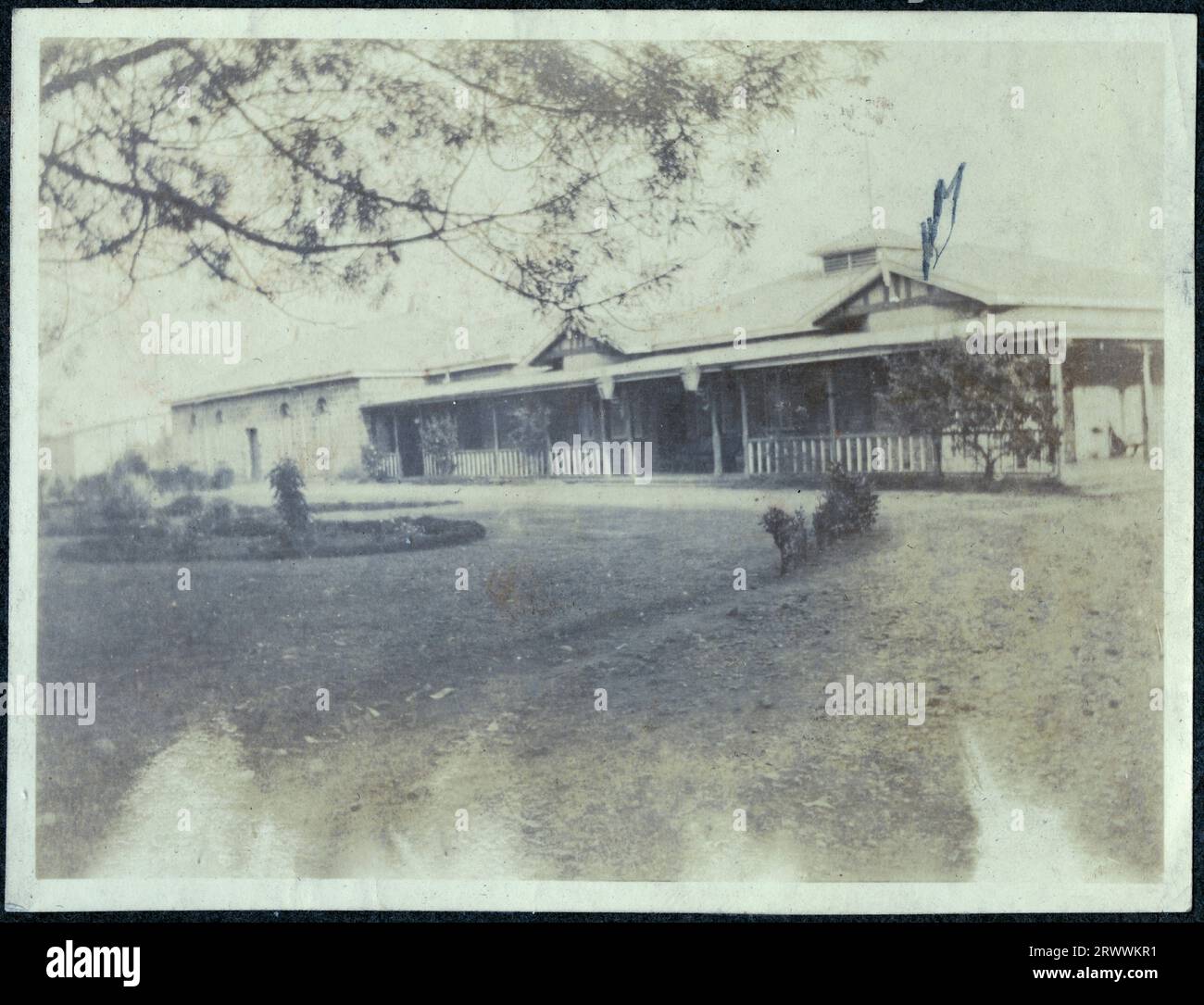 Front elevation of the Nakuru Hotel, a large one storey building with a veranda along the front. There are landscaped gardens in front. The manager of this hotel at one time was William Walter Bungey, Charles Bungey's older brother. Original manuscript caption: Nakuru Hotel [B.E.A.]. Stock Photo