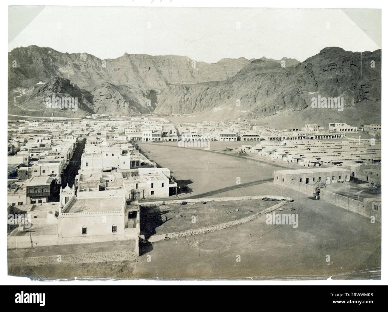 View of Aden, taken from a high vantage point with rocky mountains in the background. The buildings within the city are laid out in a grid-like formation. Caption reads: Aden. Stock Photo