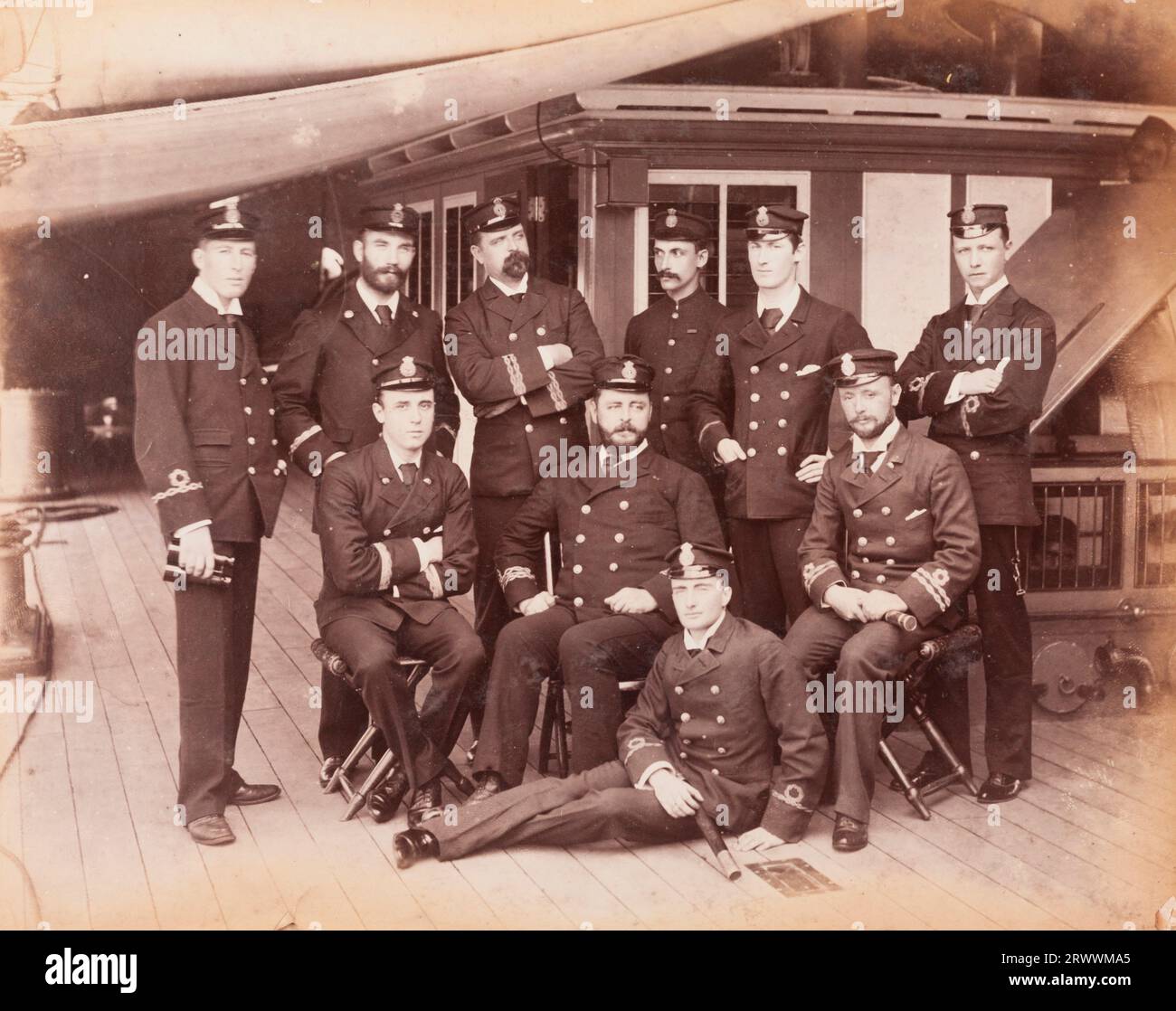 A group portrait of ten naval officers in full uniform on the deck of R.I.M.S Minto. Handwritten caption reads: Officers of R.I.M.S. Minto (1905). Stock Photo